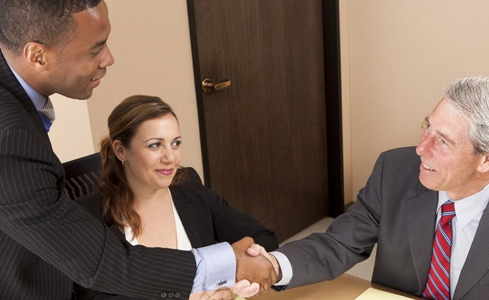 Image of professionally dressed people shaking hands in a meeting