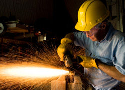 Image of man in safety gear grinding metal